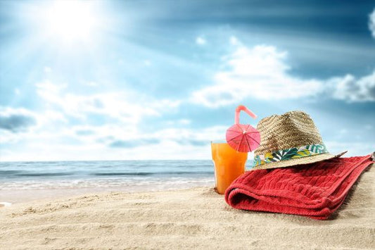 Fotografija pješčane plaže, osunčanog neba, na pijesku složen ručnik i šešir